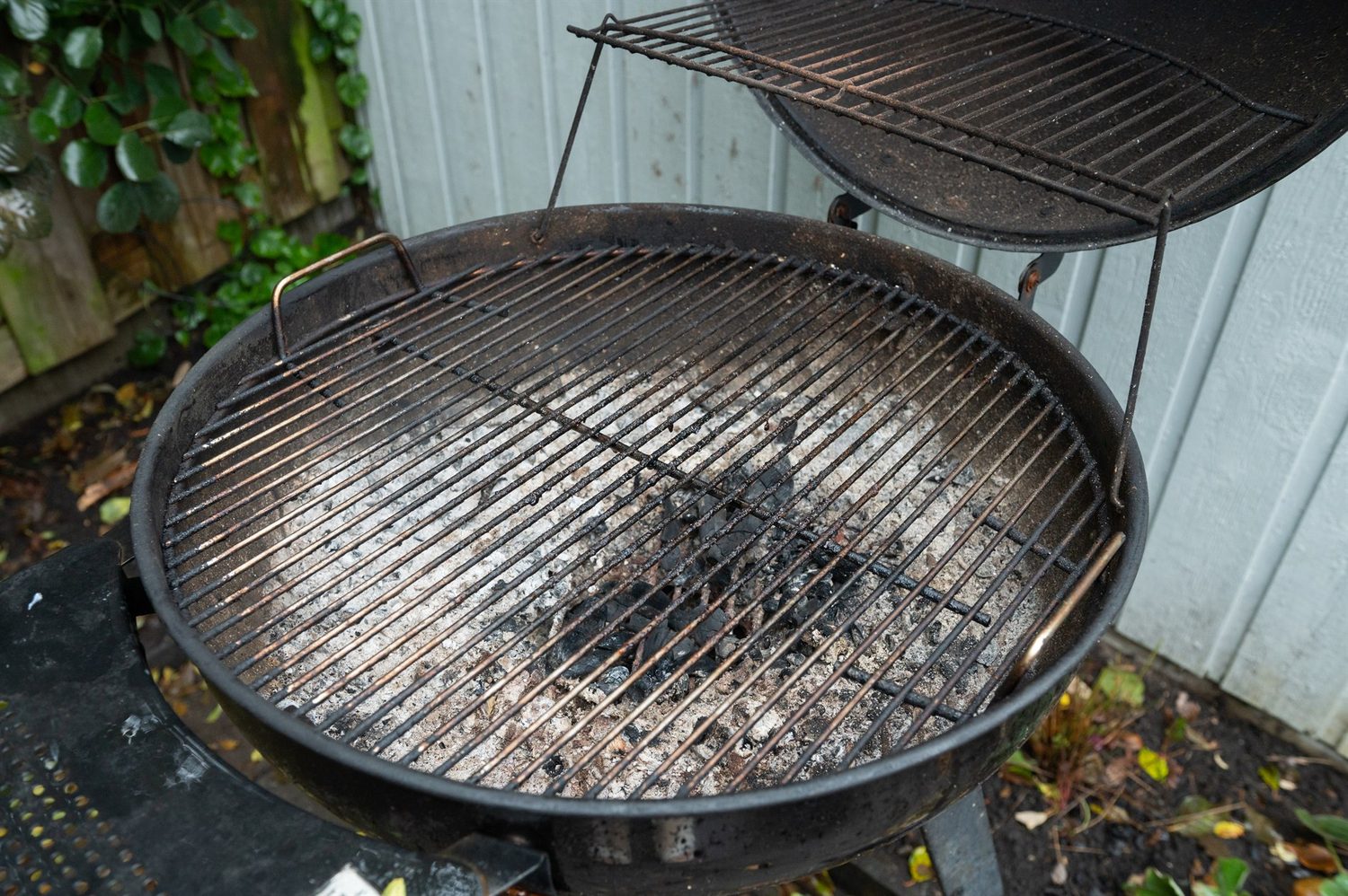 Barbacoa de exterior usada, con ceniza y restos carbonizados sobre la parrilla metálica