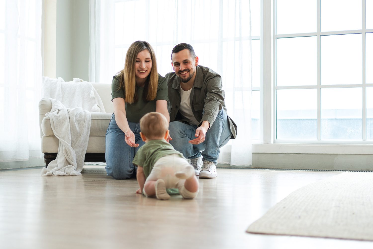 Bebé gatea por el suelo del salón hacia sus padres