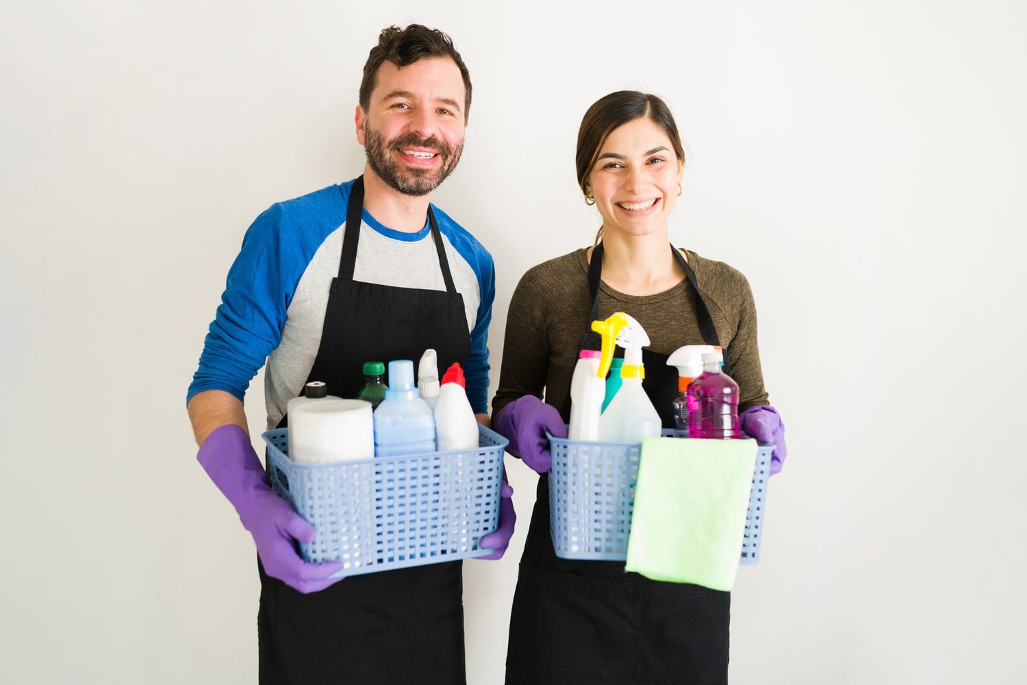 Dos profesionales con guantes y cestas de productos de limpieza preparados para trabajar
