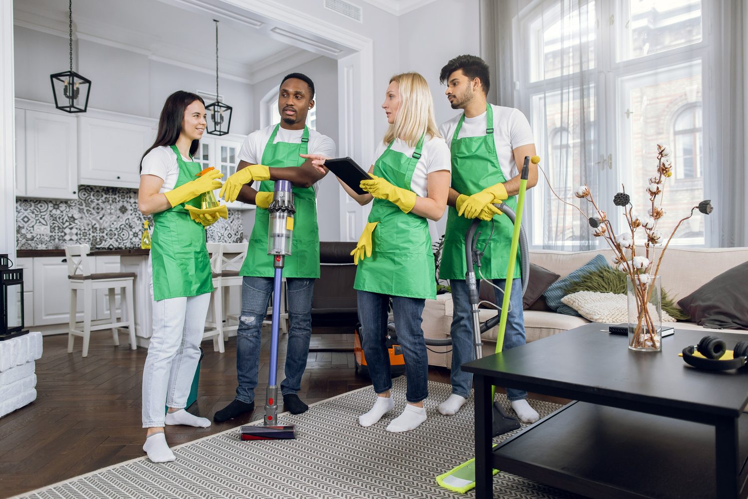 Equipo de cuatro profesionales de limpieza se reúne con sus utensilios en un salón