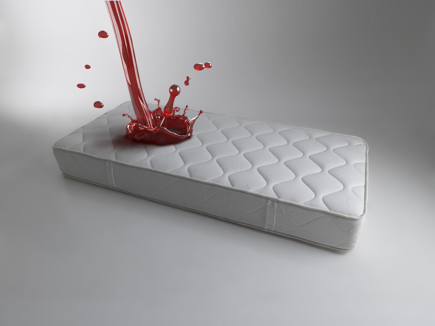 Líquido rojo cayendo sobre un colchón blanco en una composición de estudio