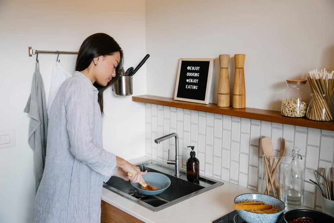 Mujer lava un plato con un cepillo en el fregadero de una cocina